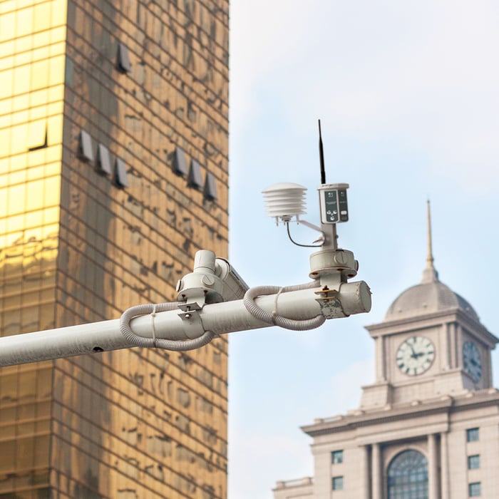 A weather station attached to a street light, including an IoT air quality monitor for data collection.