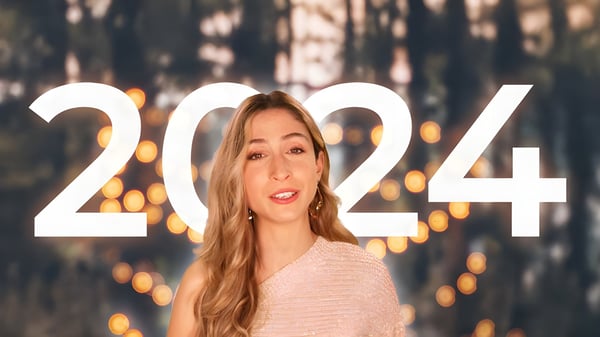 Woman speaking in front of large white 2024 text overlay with a blurred background of trees and lights.