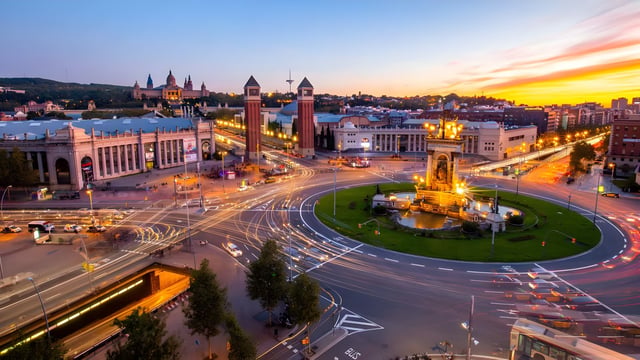 Long exposure aerial view of Plaça d'Espanya in Barcelona at sunset with light trails from traffic around the fountain.