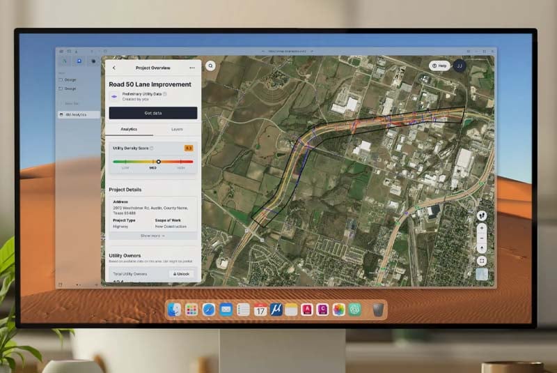Computer monitor displaying a 4M Analytics digital utility mapping interface with a satellite view of a highway and project data.