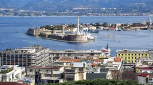 Elevated view of the port of Messina, Italy, featuring the Madonnina monument, harbor, and surrounding city buildings