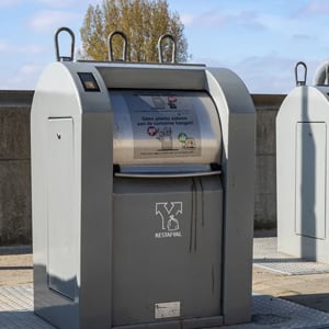 An underground waste container with Dutch signage for residual waste on a paved street under a blue sky
