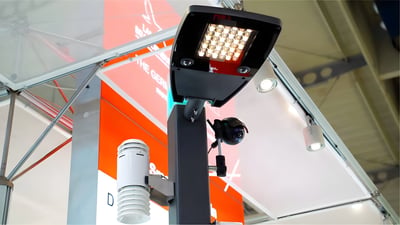 A smart street pole equipped with an LED luminaire, a security camera, and an environmental sensor at a trade show booth.