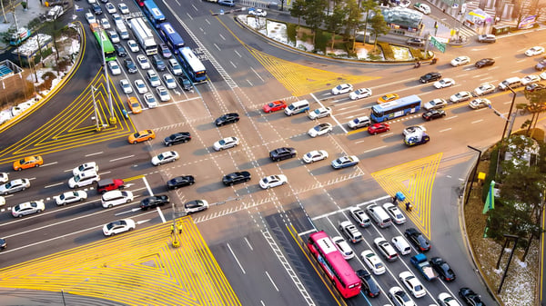 High-angle view of a busy multi-lane city intersection in South Korea with cars and buses navigating yellow crosswalks.