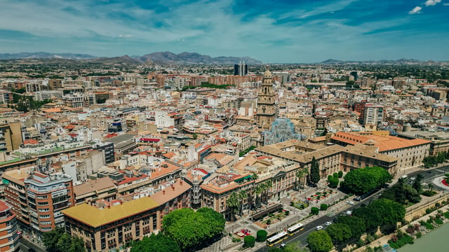 Aerial drone photograph of the city of Murcia, Spain, showing the cathedral tower and urban landscape under a blue sky