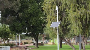 A solar-powered camera mounted on a white pole in a grassy park with trees in Yokine, City of Stirling