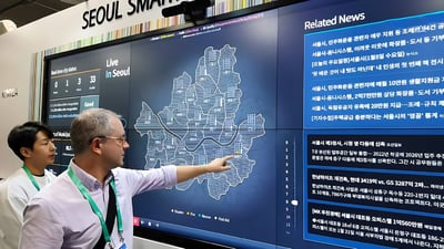 A man points to a digital map of Seoul on a large touchscreen display at a Seoul Smart City platform exhibit.
