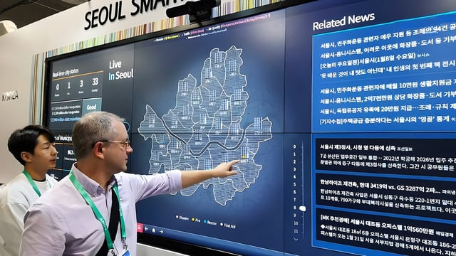 A man points to a digital map of Seoul on a large touchscreen display at a Seoul Smart City platform exhibit.