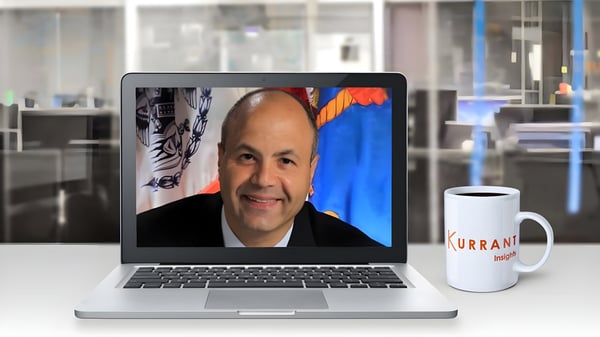 Spiro Kattan on a laptop screen next to a Kurrant Insights coffee mug in a blurred office setting.
