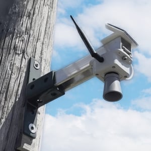 An IoT flood monitoring device mounted on a wooden pole.