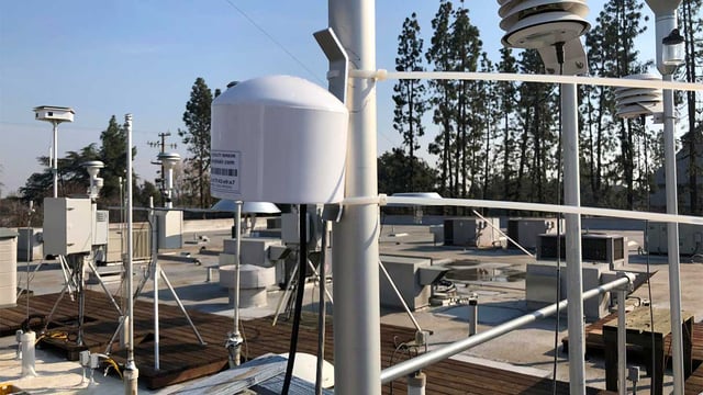A purpleair low cost air monitor sensor installed on a residential roof.