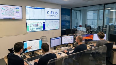 Operators in a Cielis control room monitor maps and data on multiple computer screens and a large wall display.