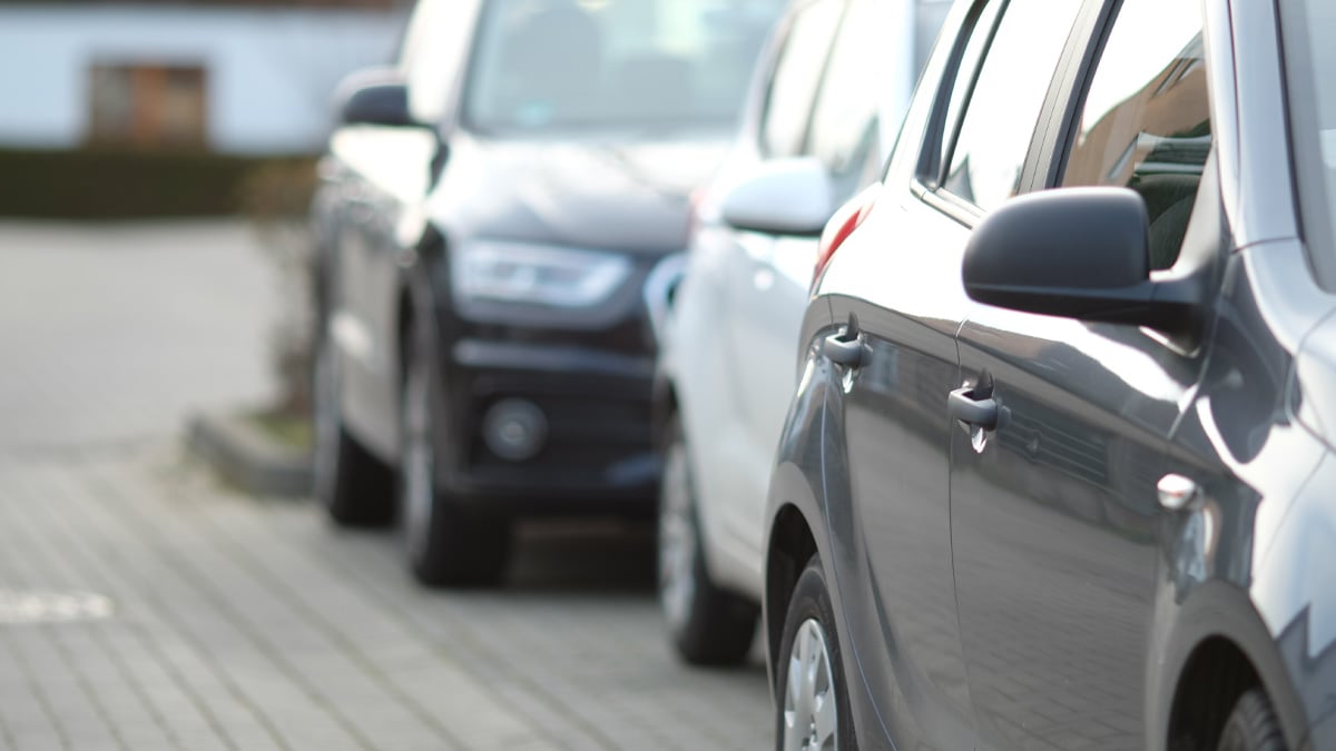 Close-up of cars parked in a row along a paved city street, with the nearest grey vehicle in sharp focus