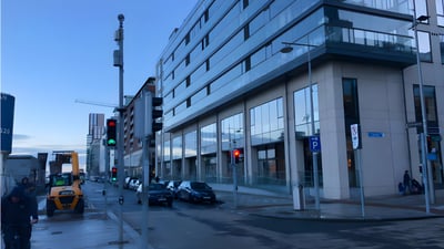 Small cell 5G nodes mounted on a street pole in front of a modern glass office building in Dublin.