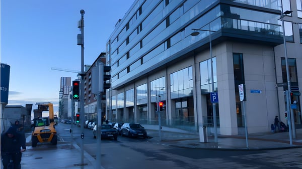 Small cell 5G nodes mounted on a street pole in front of a modern glass office building in Dublin.