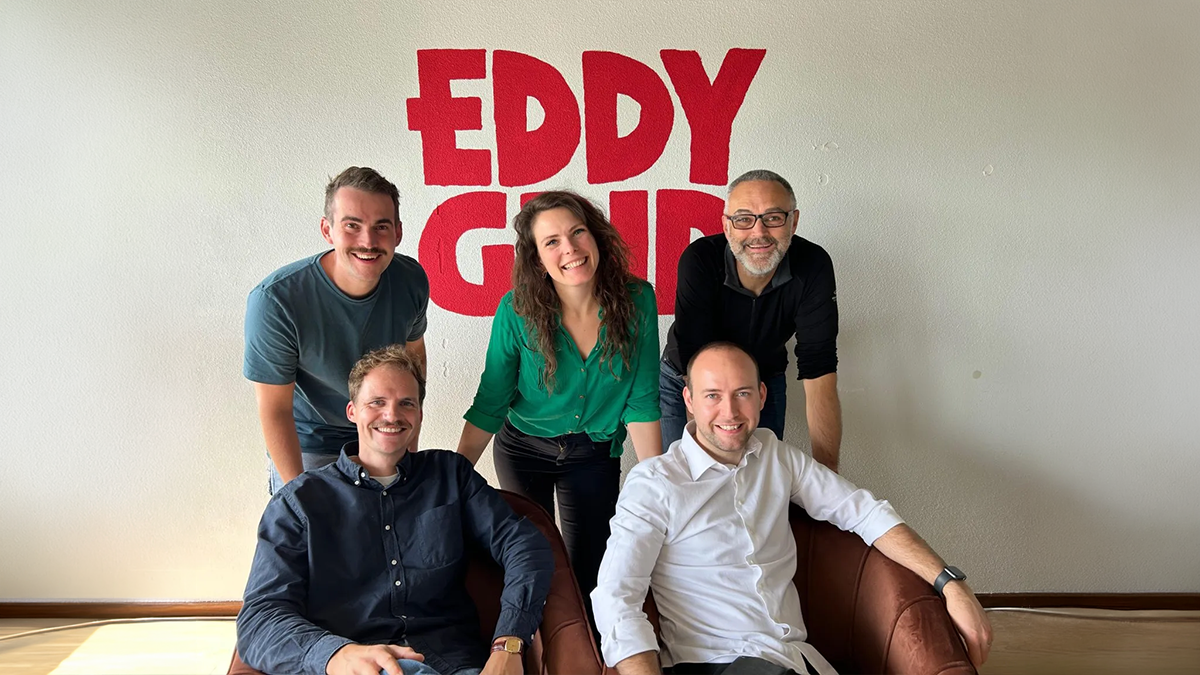 Five people posing for a group photo in front of a white wall with a red Eddy Grid logo.