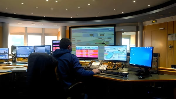 An operator monitors water utility data on multiple screens and a large projection in an Eaux de Marseille control room.