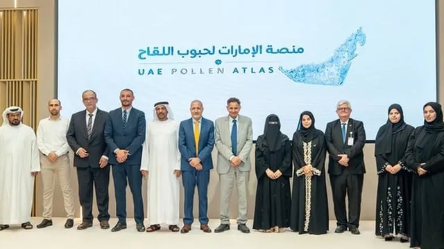 A group of officials stands in front of a screen displaying the UAE Pollen Atlas logo at a launch event.