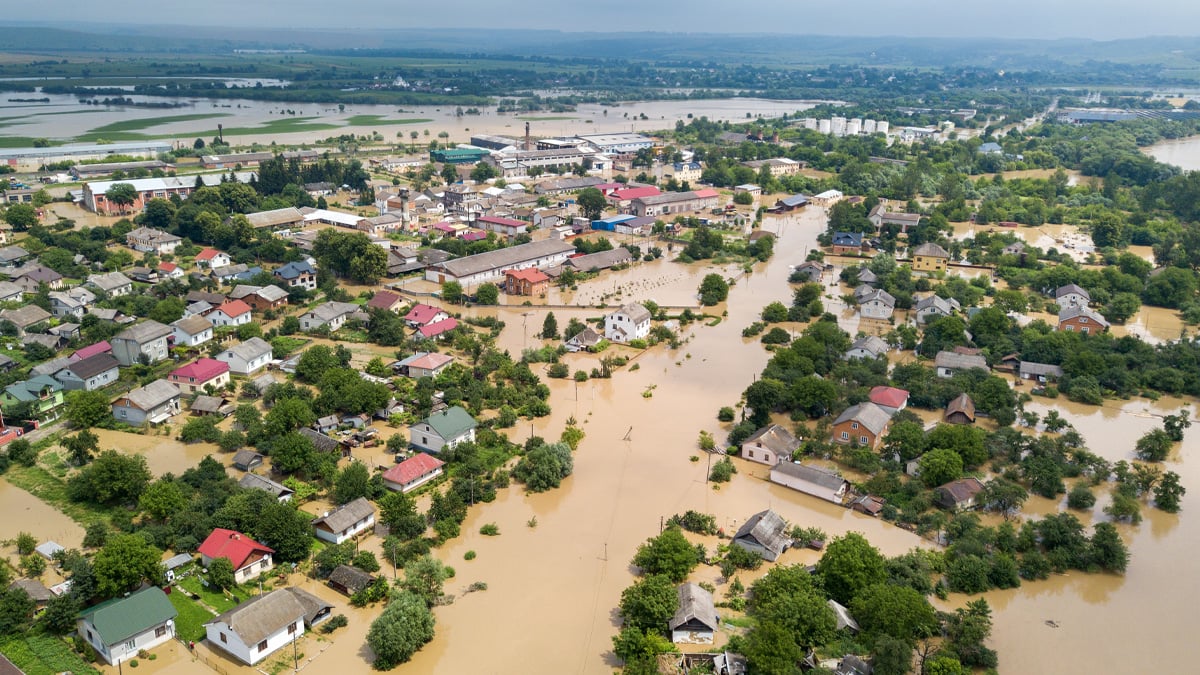 Aerial drone photograph of a residential neighborhood with streets and yards submerged in brown floodwater