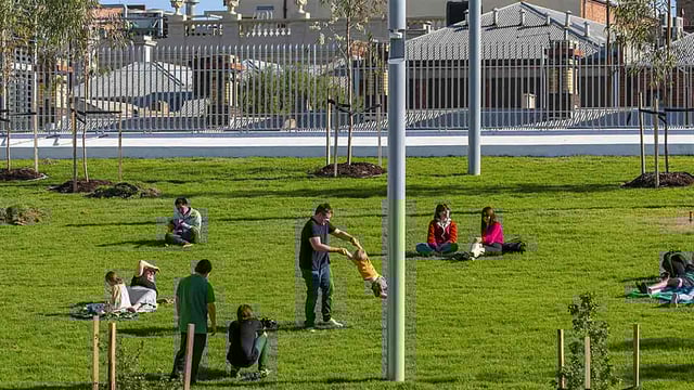 People sitting and playing in a park equipped with smart lighting in the city of Stonnington, Australia during daytime.
