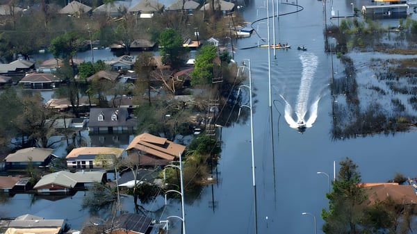 Aerial view of a motorboat traveling down a flooded New Orleans residential street with houses submerged in water.