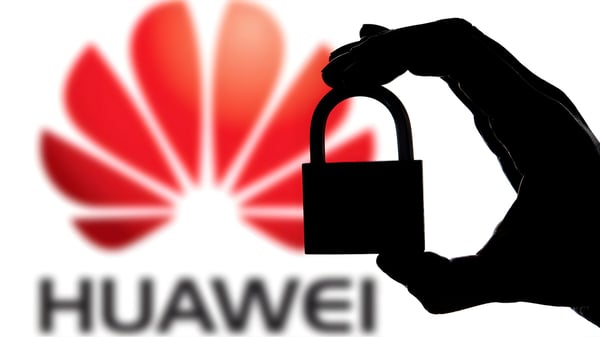 Silhouette of a hand holding a padlock in front of a blurred Huawei logo.