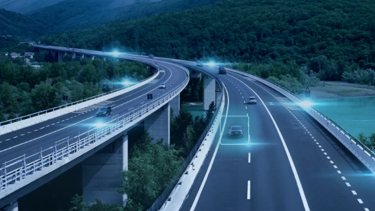 Elevated highway curves through a forested valley with digital blue light overlays on vehicles and infrastructure