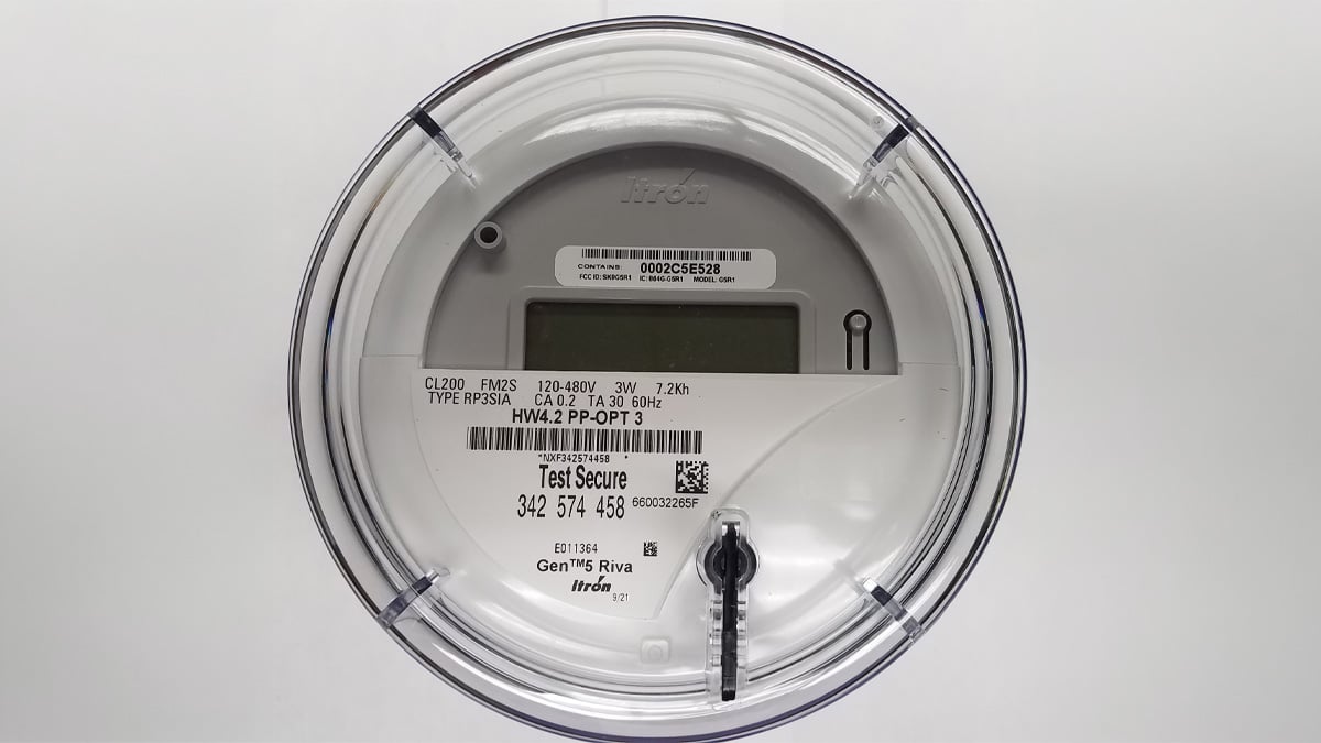 Close-up of a smart utility meter with a digital display, barcode, and "Test Secure" text on a white background.