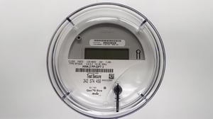 Close-up of a smart utility meter with a digital display, barcode, and "Test Secure" text on a white background.