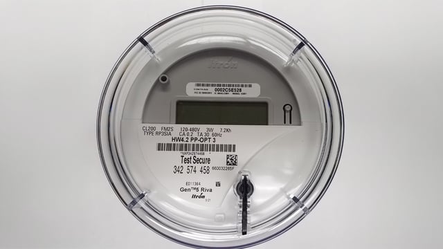 Close-up of a smart utility meter with a digital display, barcode, and "Test Secure" text on a white background.