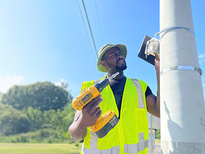 Engineer installing an air quality sensor on a pole