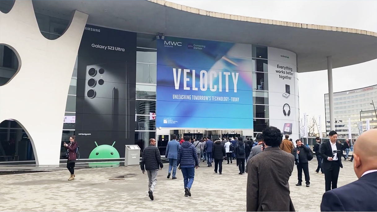A group of people walking in front of the mobile world congress building in Barcelona.