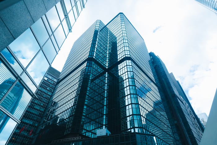 Low-angle view of modern glass skyscrapers reflecting the sky in a dense urban downtown district