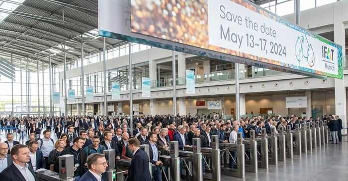 A large crowd of attendees entering turnstiles at a convention center under a banner for IFAT Munich 2024.