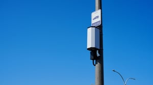 Voltpost EV charger unit mounted on a gray lamppost against a clear blue sky, with a small sign above it.