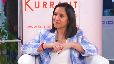 Woman in a blue and white checkered blazer seated in front of a Kurrant Insights banner.