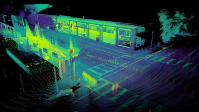 LiDAR point cloud scan of a transit station platform and street intersection in neon green and purple heat map colors.