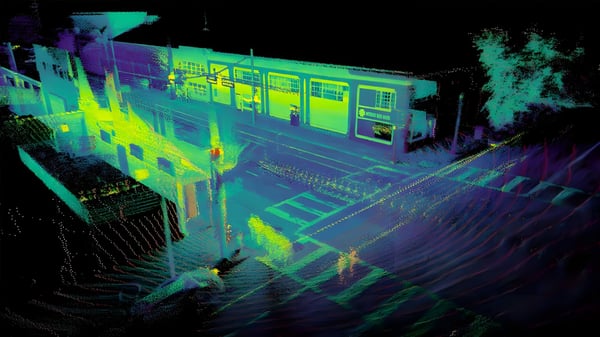 LiDAR point cloud scan of a transit station platform and street intersection in neon green and purple heat map colors.