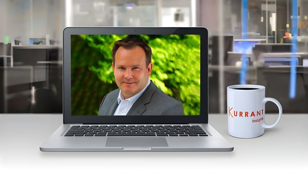 Mark Dancy on a laptop screen next to a Kurrant Insights coffee mug in a blurred office setting.