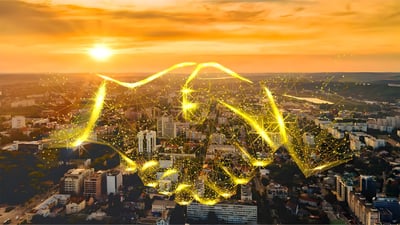 Digital handshake graphic overlaid on an aerial view of a city skyline at sunset.