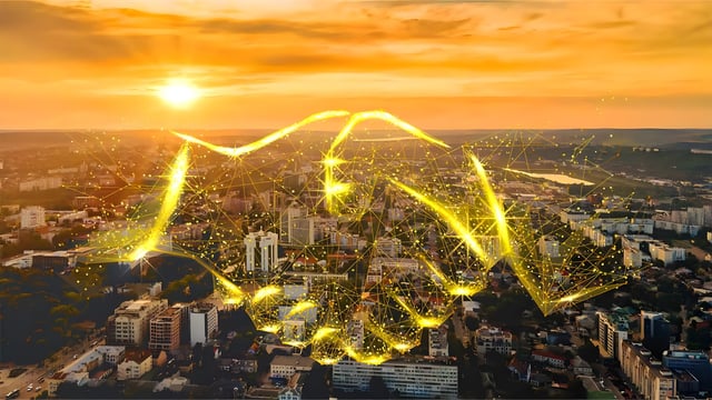 Digital handshake graphic overlaid on an aerial view of a city skyline at sunset.