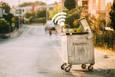 Photo of a waste container equipped with an IoT fill level sensor emitting a signal.