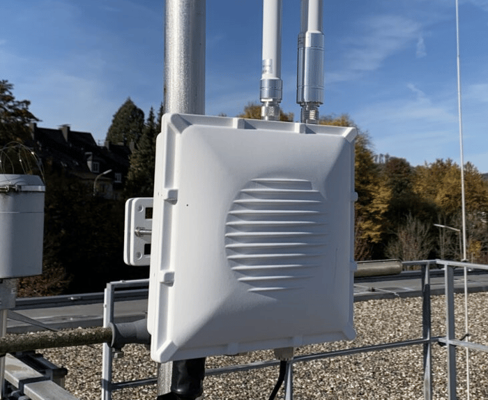 A white antenna on top of a building, serving as a LoRWAN gateway for communication signals.