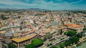 Aerial drone photograph of the city of Murcia, Spain, featuring the cathedral tower and surrounding urban buildings