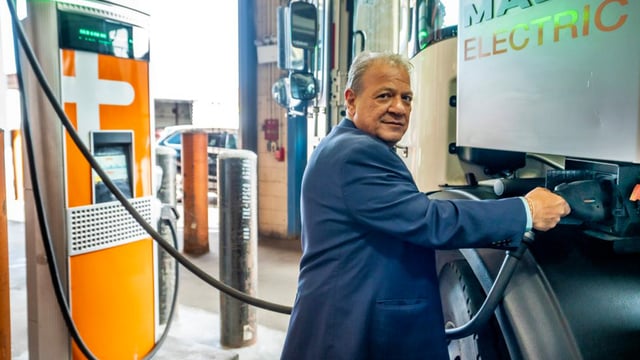 A man using an ev charger to charge a fleet vehicle in new york city