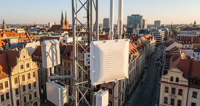 LoRaWAN gateway antennas mounted on a metal tower overlooking a European city with historic red-roofed buildings