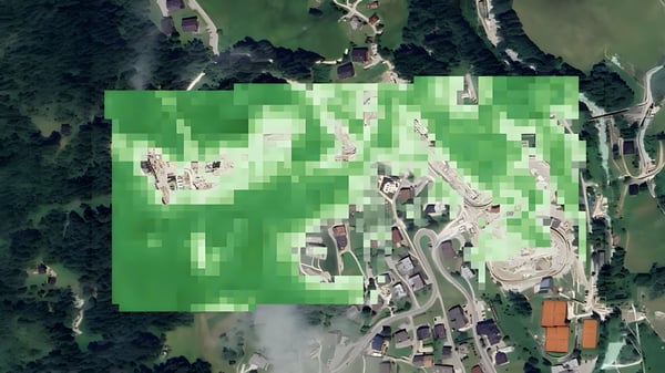Satellite view of a rural landscape with a green pixelated data overlay covering buildings and roads.