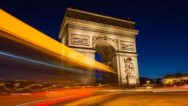 A photo of Paris at night featuring the Arc de Triomphe illuminated by smart street lights