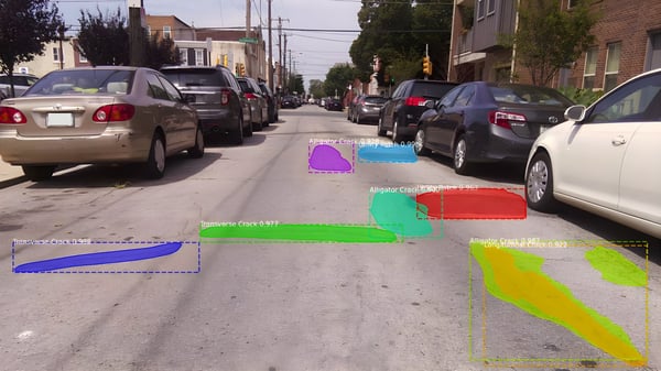 AI software identifying road surface cracks with colorful digital overlays on a narrow Philadelphia residential street.