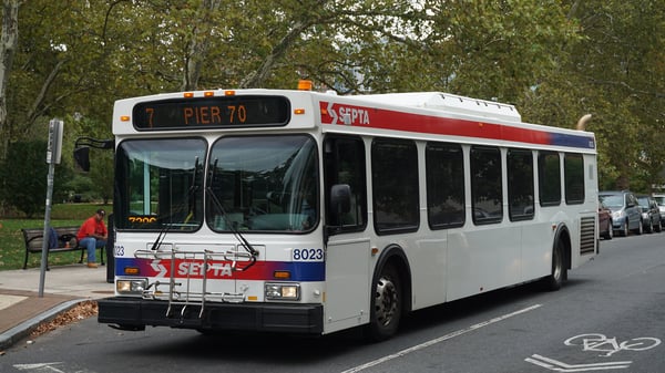 A SEPTA transit bus displaying Pier 70 on its destination sign drives on a Philadelphia street next to a bike lane.